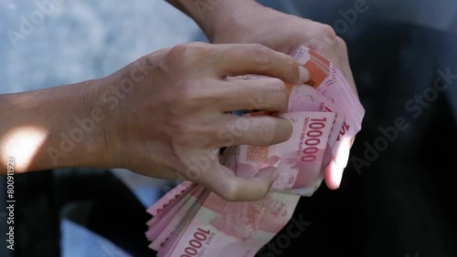 A man counting a pile of hundred thousand rupiah notes. A businessman counting cash. The concept of investment, exchange, salary, credit, deposits. 