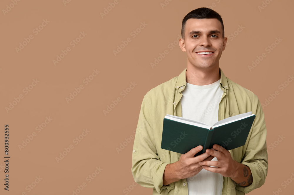 Handsome young man reading book on beige background Handsome young man reading book on beige background