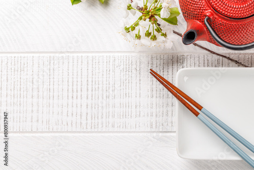 Table adorned with cherry blossom branch and chopsticks, epitomizing Japanese food culture