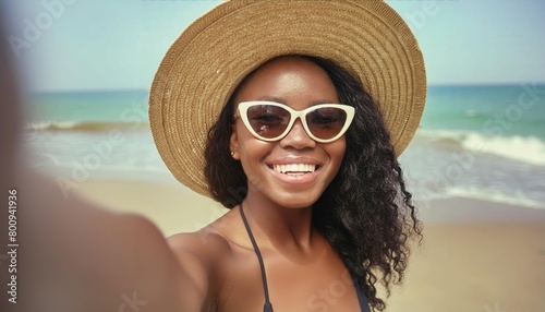 Happy young woman in straw hat and sunglasses takes a selfie on the beach 