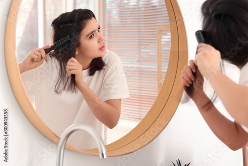 Young woman combing hair in...