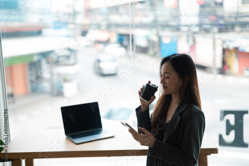 Young woman enjoying a cup of coffee alone in a cafe or bar and using smartphone.