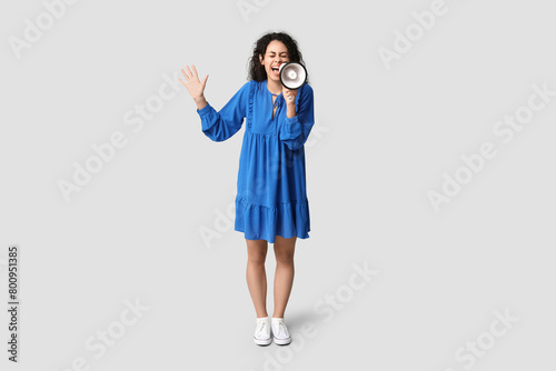 Screaming African-American woman with megaphone on light background © Pixel-Shot
