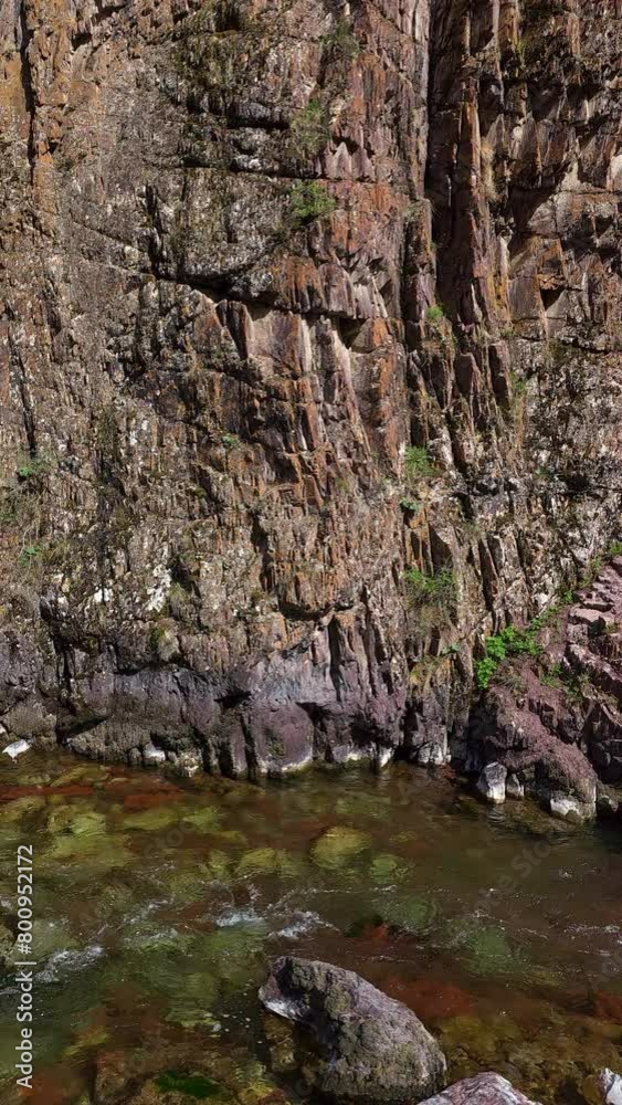 mountain river under vertical wall of rock in the mountains at sunny spring day, side view mountain river under vertical wall of rock in the mountains at sunny spring day, side view