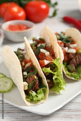 Delicious tacos with meat and vegetables on wooden table, closeup