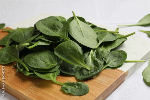 Board with fresh spinach leaves on white table, closeup