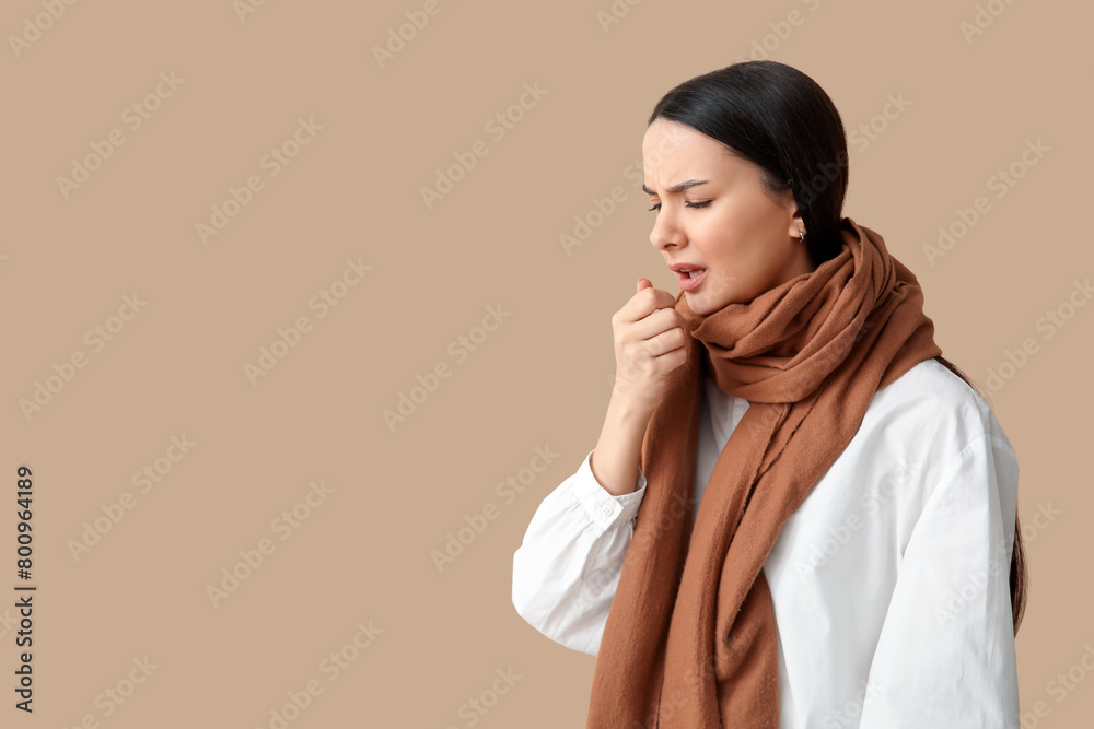 Beautiful young woman in scarf suffering from sore throat on brown background Beautiful young woman in scarf suffering from sore throat on brown background