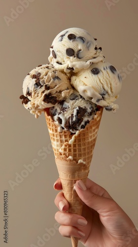 A hand holding an ice cream cone filled with cookies and chocolate chips