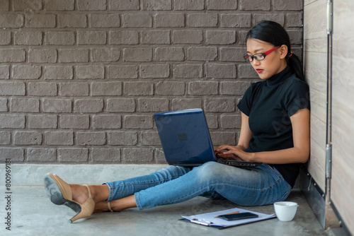 a workingwoman is sitting on the floor using laptop photo