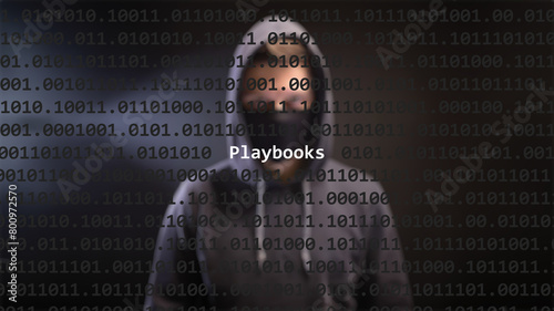 Cyber attack playbooks text in foreground screen, anonymous hacker hidden with hoodie in the blurred background. Vulnerability text in binary system code on editor program.