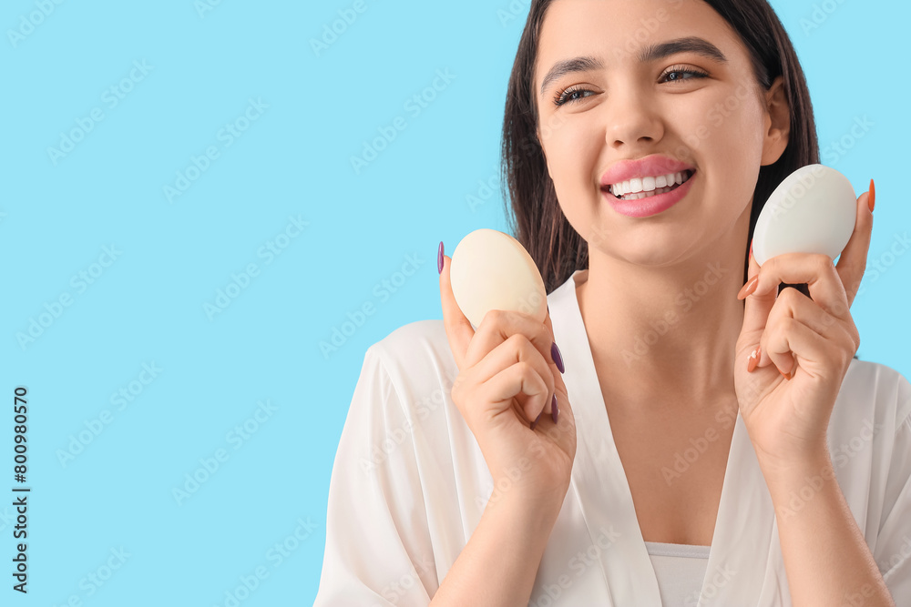 Young woman with soap bars on blue background, closeup Young woman with soap bars on blue background, closeup