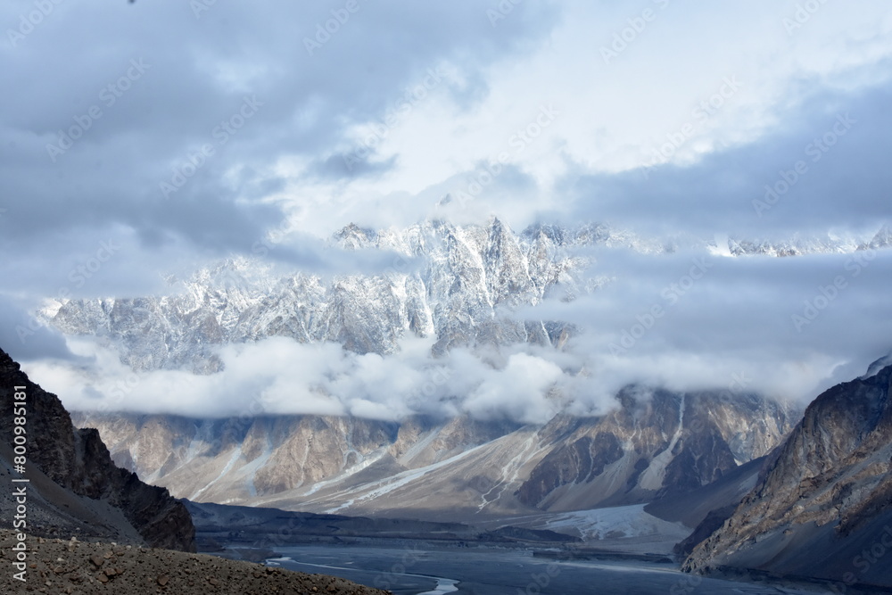 Legendary Passu cones shrouded in clouds in winter season and a river flowing quietly below.