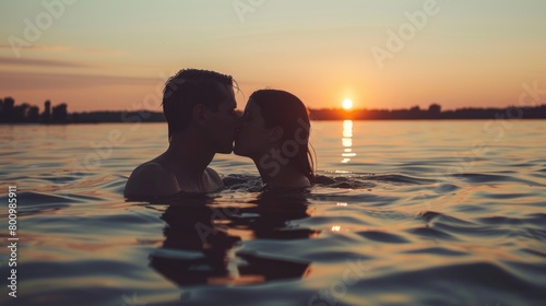A couple kissing in the ocean at sunset