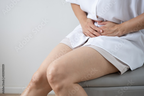 The figure of a woman wearing a white shirt is sitting with her hands on her stomach or uterine area  cervical cancer disease concept