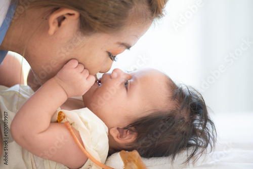 A mother plays with her little daughter in a bedroom full of warmth and family.