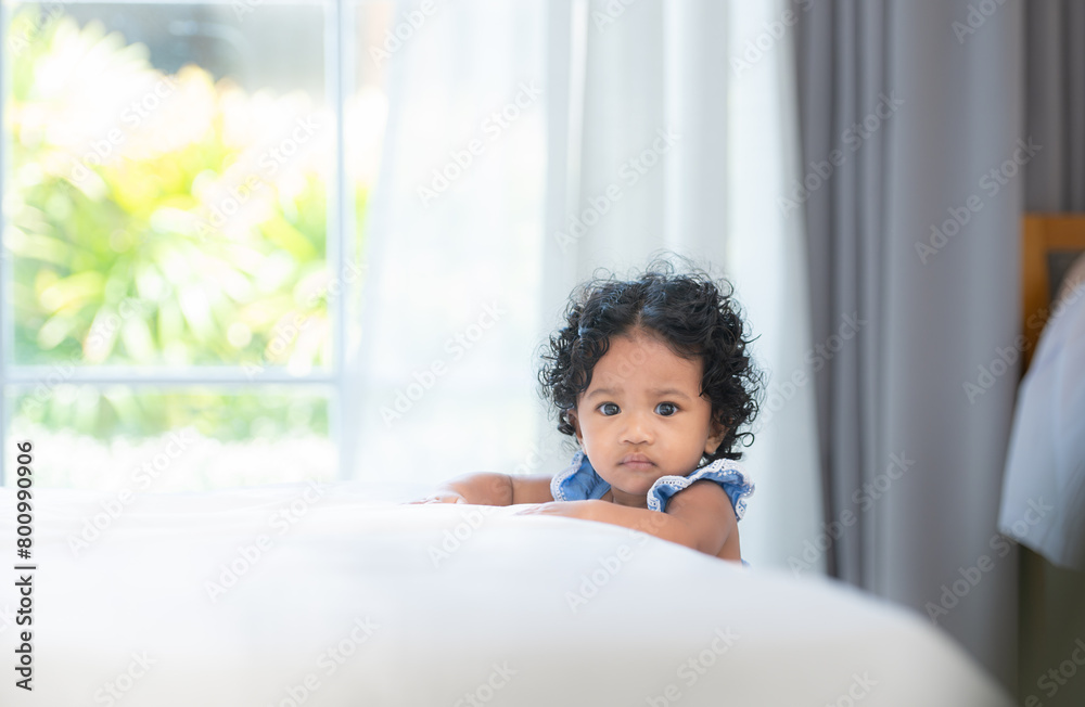 A little girl with a big smile sits on a bed in a sunny room, radiating happiness and joy A little girl with a big smile sits on a bed in a sunny room, radiating happiness and joy