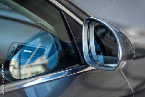 Grey car door and window detail with rear-view mirror, reflections on the glass surface