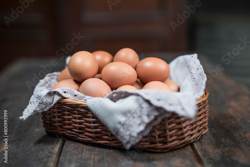 Chicken eggs in a lined basket on an old rustic wooden table. Natural healthy food in a vintage setting still life