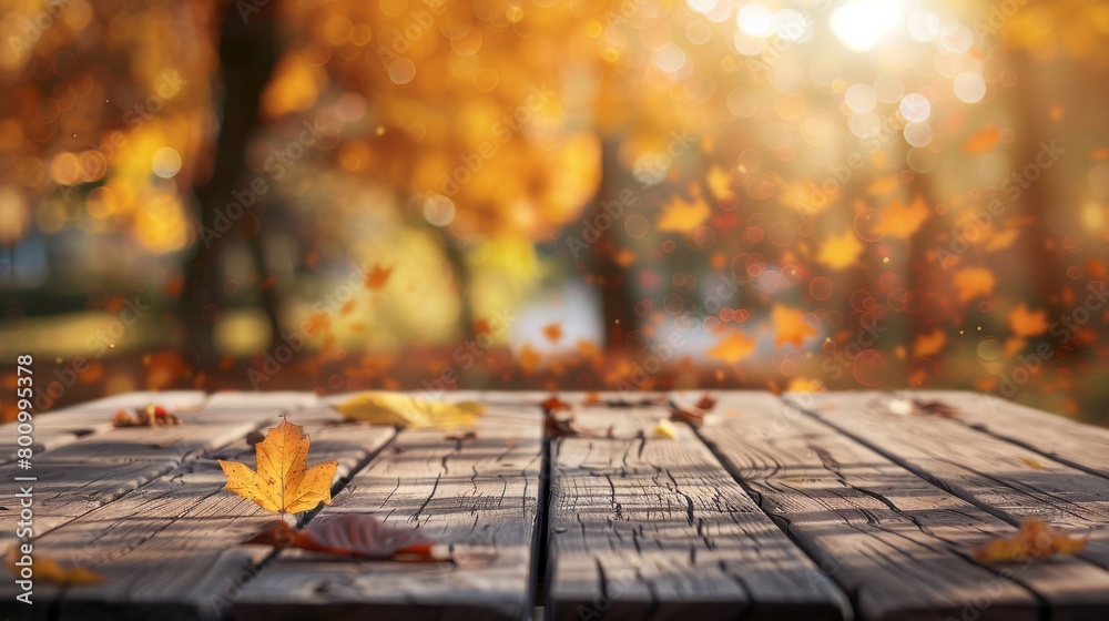 Autumn, yellow leafs on an empty wooden table, blurry background with sunlight