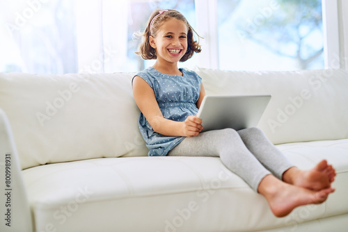 Portrait, tablet and happy girl child in home on sofa for game, show or streaming movie online in living room in Canada. Kid, smile and digital tech in lounge for learning, education or watch cartoon