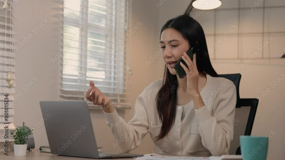 a beautiful Asian woman is working from home in her office and talking on the mobile phone about details of an important information of report, talking on the phone with friend happily and smiling a beautiful Asian woman is working from home in her office and talking on the mobile phone about details of an important information of report, talking on the phone with friend happily and smiling