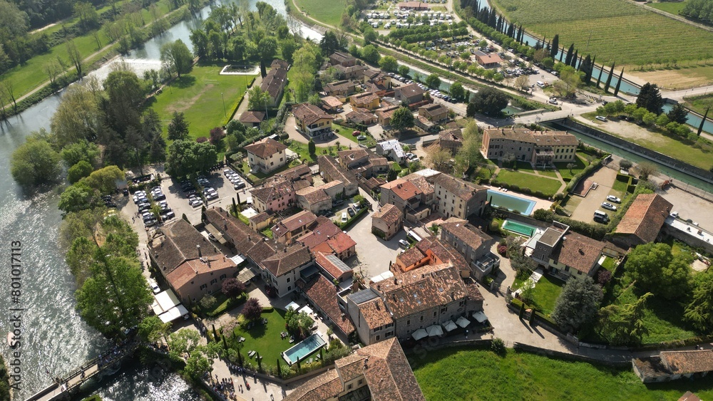 Beautiful little village aerial view of the mill village of Borghetto sul Mincio in the south of Lake Garda, in Veneto, Italy. Drone footage of the small medieval village 