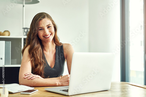 Portrait  woman and laptop in modern office for business career with notebook  check email and reading online news. Female consultant  notes and tech by desk for smile  connection and client advice