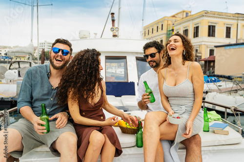 Two happy couples share laughter and drinks during a casual yacht party, epitomizing carefree summer fun at the marina. (ID: 801018998)