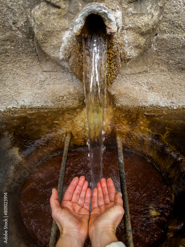 Catching Water from an Ancient Stone Fountain