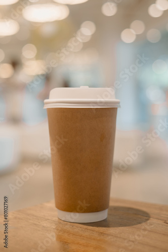 Hot coffee in a tall disposable paper cup with bokeh background