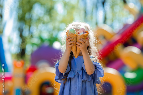 happy little girl eats ice cream in the park in the summer