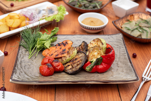 grilled vegetables on a plate on the table against a wood background serving