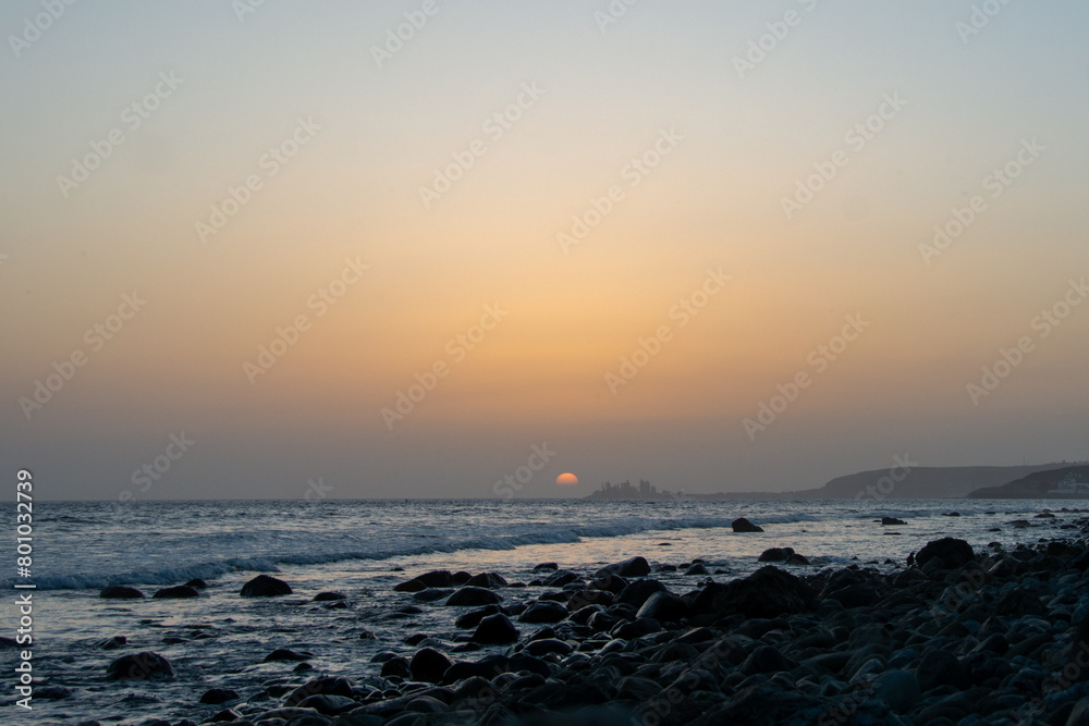 Beautiful orange sunset over the sea with stones on the beach Beautiful orange sunset over the sea with stones on the beach