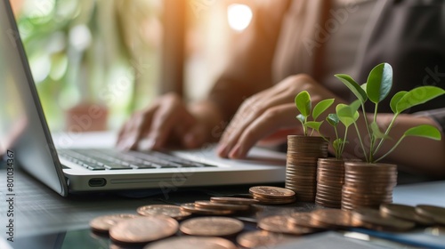 A person working on a laptop, with a growing plant on a pile of coins.
