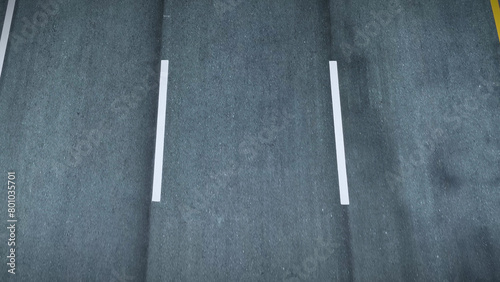 The recently laid asphalt road exhibits a uniform texture, free from cracks and irregularities. A car maneuvers along the motorway with precision, showcasing the engineering excellence. POV view. 