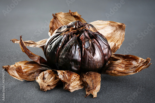 Bulb of black garlic on gray background.