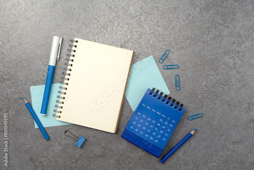 Notebook and blue stationery on stone texture background. Work desk space