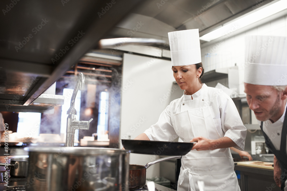 Man, woman and professional kitchen or chef cooking in dine dining restaurant, hospitality or food industry. Teamwork, pan and meal preparation with collaboration for job with stove, lunch or gourmet