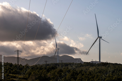Silhouetted power lines and windmills against the backdrop of a sunset sky signify park eolic and the quest for green energy and environmental harmony