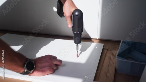 Caucasian man assembles furniture fit table or mount wardrobe, hammers nail and screwdriver screw. Adult craftsman close-up hands does home repairs