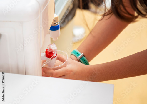 Close-up of a girl's hands pours hot water from the drinking boiler or dispenser