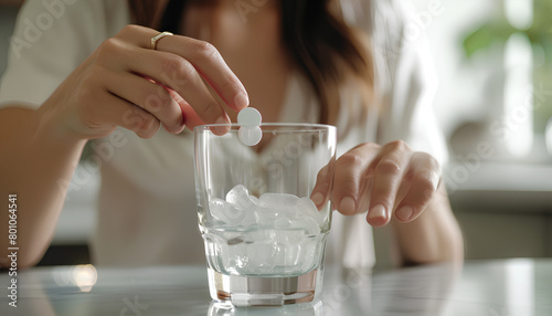 Woman putting effervescent tablet into glass of water, closeup