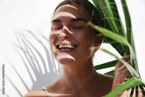 Young Woman with Shadow of Palm Leaves on White Wall