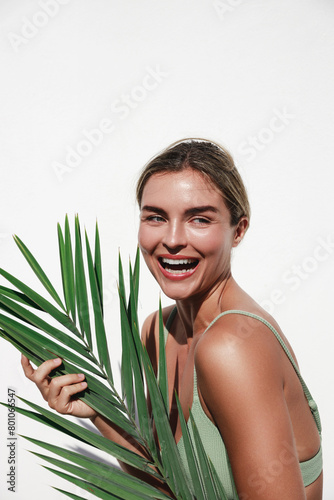 Portrait of Beautiful Young Woman Posing with Palm Leaf on White Background