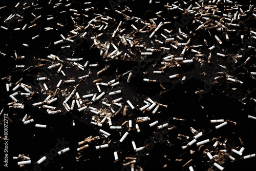 Lots of cigarette butts on black background, Dirty backdrop for banner about the dangers of smoking and toxicity.