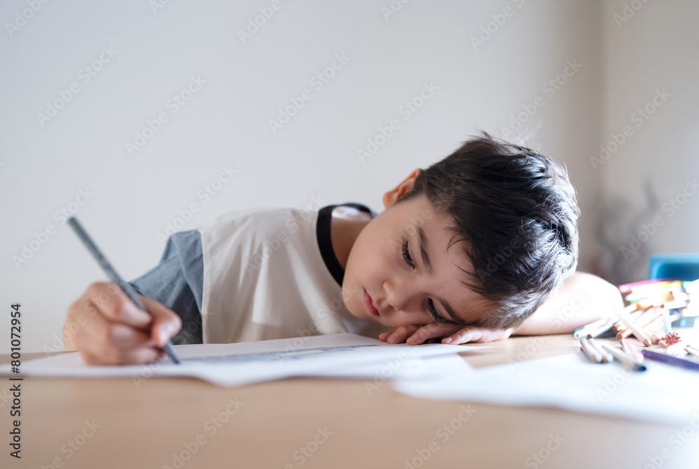 School kid writing or painting for homework, Child bored face lying head down looking out deep in thought, Boy learning online class room at home, E-learning or Homeschooling education concept School kid writing or painting for homework, Child bored face lying head down looking out deep in thought, Boy learning online class room at home, E-learning or Homeschooling education concept