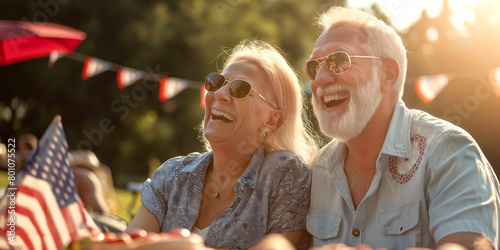 Happy cheerful couple having great time at at BBQ party. Elderly man and woman celebrating 4th of July outdoors with their friends and family. © MNStudio
