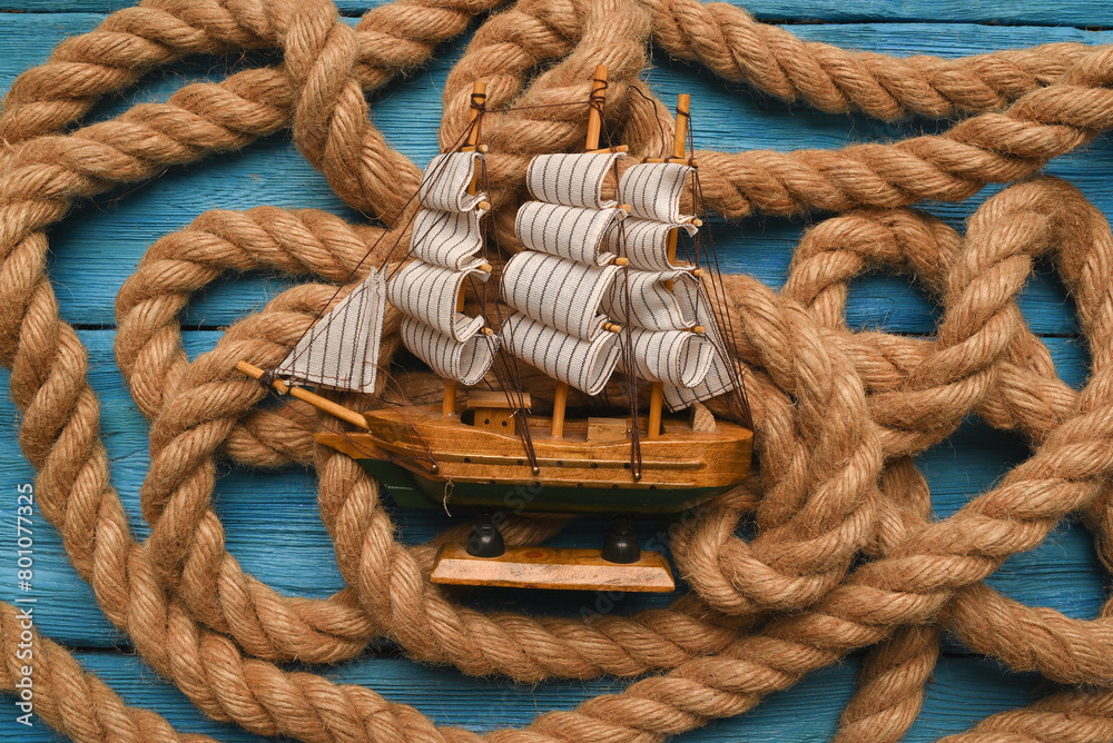 Columbus day concept background. Toy ship on the moorings rope flat lay background.
