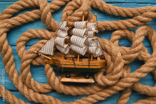 Columbus day concept background. Toy ship on the moorings rope flat lay background.