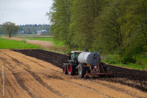 Tractor with slurry tank preparing field treated with glyphosate for cultivation by applying manure and plowing under sprayed plant residues